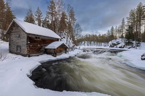 Old wooden Myllykoski water mill along the river Kitkajoki in winter, Oulanka National Park,