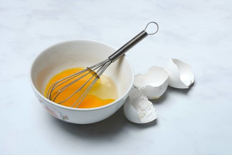 Whipped egg in shell with whisk, egg shells