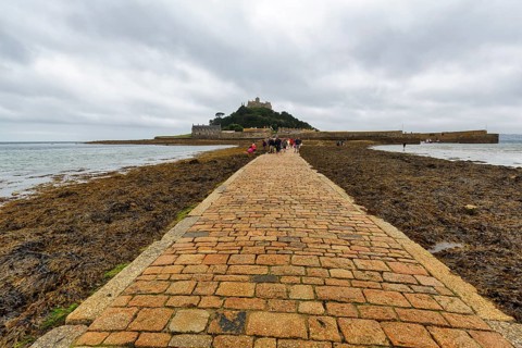 Walker, cobbled causeway, St Michael's Mount, tidal island with castle, rain clouds, Marazion,