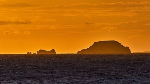 Silhouette of islands in the sea during an orange-coloured dusk with a clear sky, sunset, Kassos,