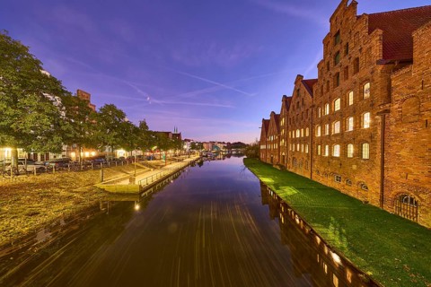 Salt warehouse, historic brick buildings, river Trave, trees, quay wall, evening blue hour, deep