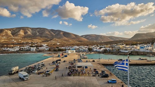 Coastal view of a harbour with a small village and mountains in the background under a blue sky