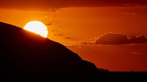 Sun disappears behind mountain, bright warm orange sky at sunset, sunset, Kassos, Karpathos,