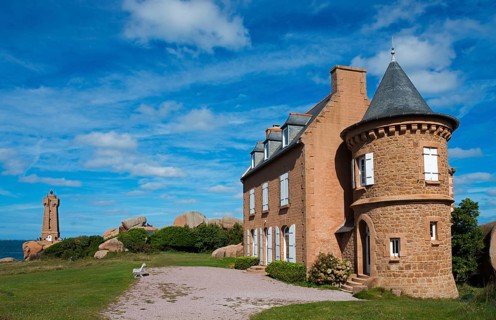 Historic castle with red stone tower under blue sky and clouds, Phare de Men Ruz and Maison Gustave