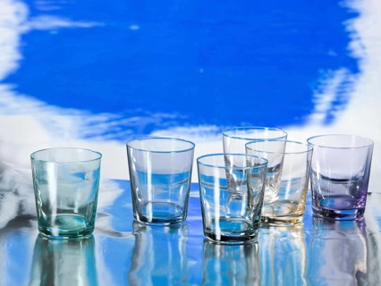 Various glasses on silver foil, blue coloured surface behind, studio shot