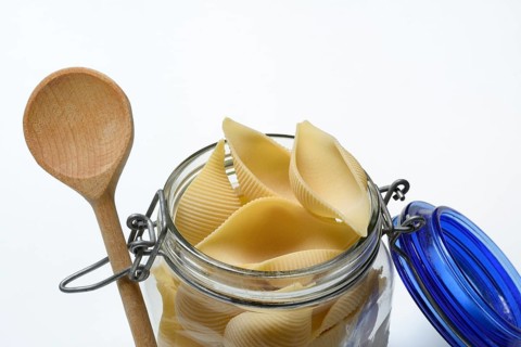 Conchiglione in glass jar with cooking spoon, Italian pasta variety