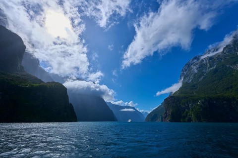 Dramatic scenery with water and cloudy sky between rock faces, summer, Milford Sound, Te Anau,