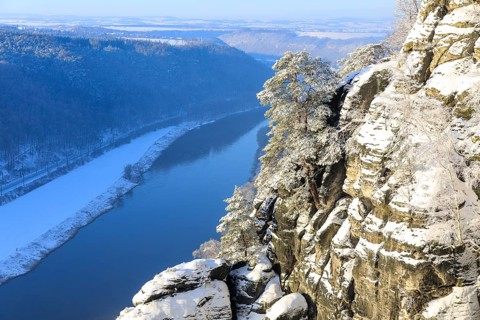 View from the Bastei Bridge into the Elbe Valley with enchanting snow-covered sandstone cliffs and