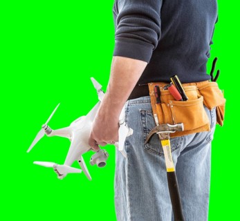 Partial view of construction worker wearing toolbelt and holding his UAV drone on green screen
