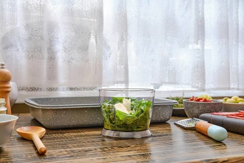 Bright sunlight filters through a window illuminating a kitchen countertop where fresh vegetables