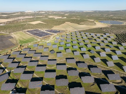 Rows of solar panels at a photovoltaic plant and the town of Espejo in the distance. Aerial view.