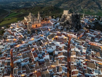 The hilltop White Town of Olvera with its La Encarnación church and Moorish castle. At dusk. Aerial