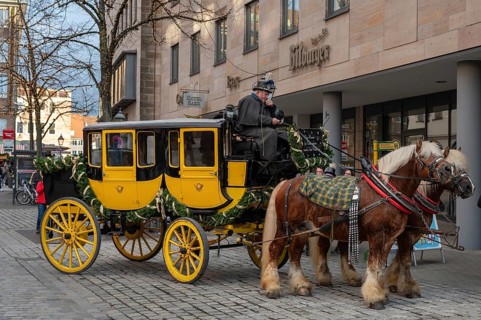 Historic stagecoach with harnessed cold-blooded horses, draught horses, round trips during the