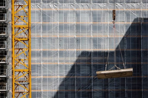 Essen, North Rhine-Westphalia, Germany - Construction crane lifts concrete section in front of