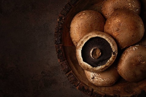 Fresh Portobello mushrooms, in a wooden bowl, top view, close-up, no people
