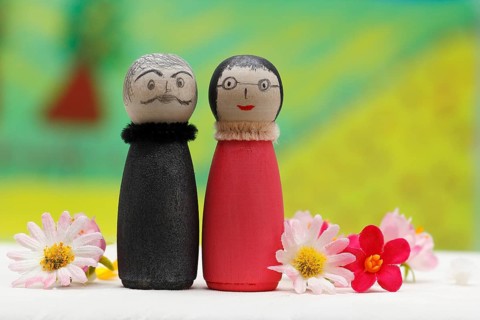 Funny painted wooden cone man and woman in front of a colourful painted background, North