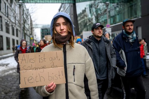 Woman with sign: Everything's fine as long as you're rich! Quote from Die wilden Kerle. At the