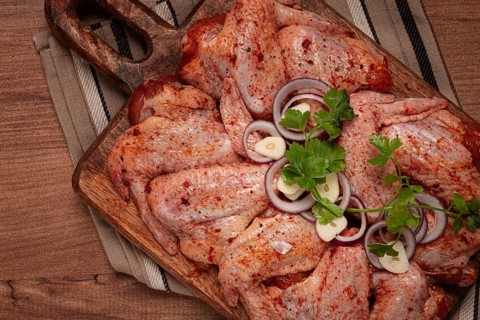 Chicken wings, marinated and laid out on a wooden platter, ready for cooking, grilling or baking,