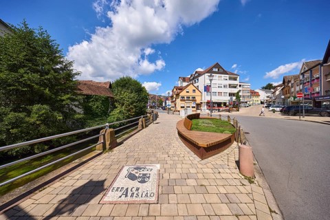 Bench, trees, blue sky with cumulus clouds, intersection of Hauptstraße and