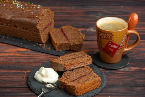Several slices of chocolate cake with whipped cream on a plate, next to a cup of coffee