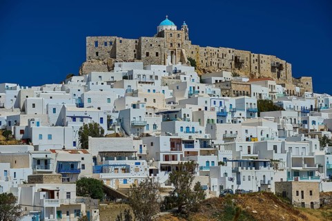 White houses on a hill under a blue sky, overlooked by a castle, Querini Castle, Chora, Astypalea,