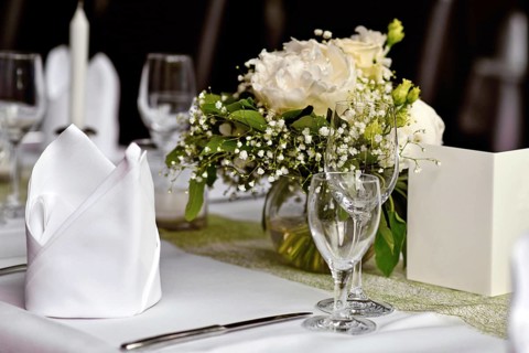 Beautiful white flower bouquets with drinking glasses and cloth napkin at Wedding table setting
