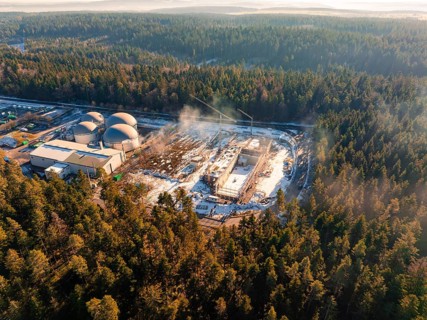 An industrial plant lies in the wintry forest, construction site with cranes, covered with snow,