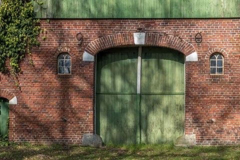 A brick wall with a large green barn door and two small windows, farmhouse, Münsterland, North