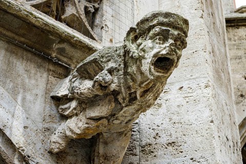 Sculpture of a male figure as a gargoyle, neo-Gothic architectural detail in the inner courtyard of