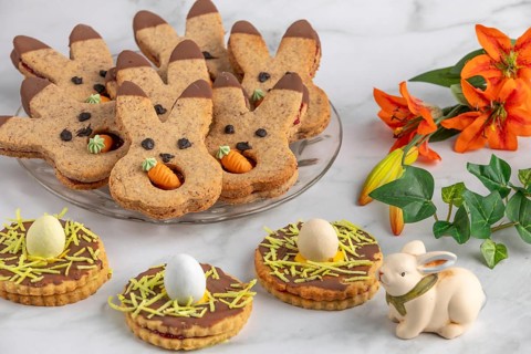Bunny biscuits with carrots and egg decoration next to orange flowers and Easter bunny
