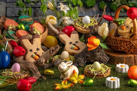 Varied Easter decorations with colourful eggs, flowers and biscuits on green grass