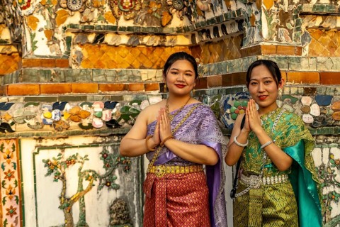 Traditionally dressed woman pose in front of the temple Wat Arun or Temple of Dawn in Bangkok,