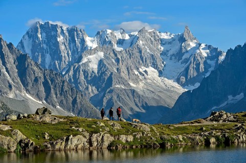 Hikers at the mountain lake Lacs des Chéserys in the Aiguilles Rouges nature reserve against the