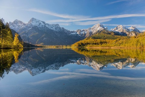 Lake Almsee in autumn with mountains reflected in the lake. Blue sky