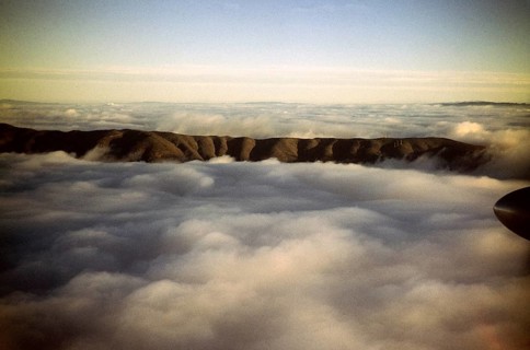 Oblique view of a mountain ridge emerging from the cloud cover, location unknown, Australia 1956