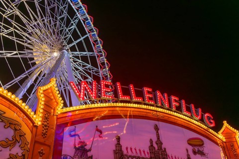 Luminous merry-go-rounds and a Ferris wheel at night at a funfair, Europa Rad, rides, wave flight,