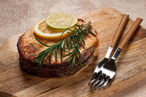 Salmon steak, fried, on a cutting board, top view, rosemary, lemon and lime, homemade, one serving,
