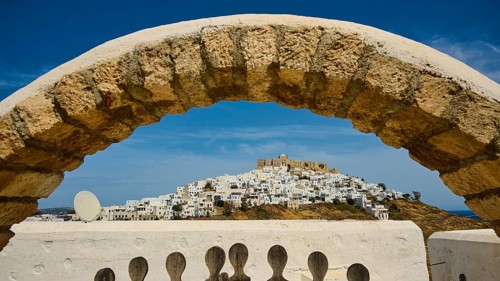 Stone arch frames the view of a hilltop village with a fortress, Querini Castle, Chora, Astypalea,