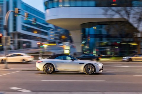 Car at night in front of urban surroundings with modern architecture, pull-along. Mercedes-Benz SL
