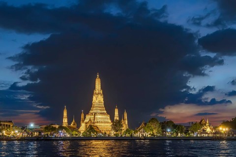 Wat Arun, Temple of Dawn at sunset with dark clouds. Boats on the Chao Phraya river. Tourist