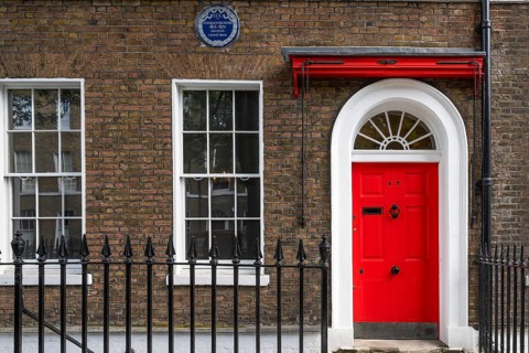 Red entrance door in a brick building with a cast-iron fence, Charles Dickens Museum, 48-49 Doughty