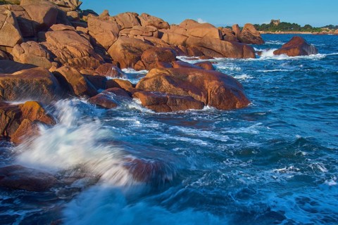 Large rocks on the Granit Rose coast, lapped by the dynamic waves of the blue sea, Ploumanach, Cote