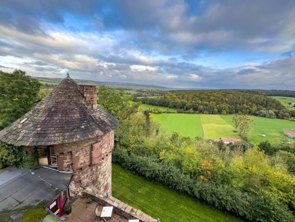 View from Trendelburg Castle to shingle roof of castle tower in the foreground behind green valley