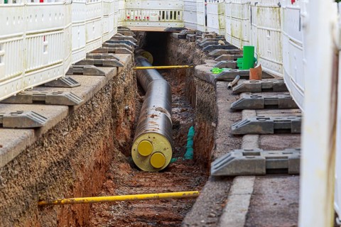 Construction trench with installed district heating pipes and safety fences at a construction site