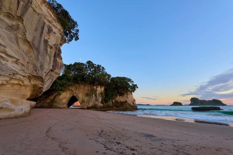 Sandy beach beach with rock and cave views, surrounded by calm seas and clear skies, Cathedral