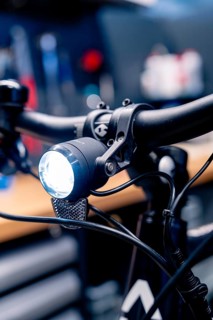 Bicycle light on the handlebars shines brightly in a workshop, focus on technological details,