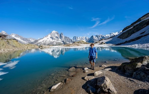 Mountaineer in front of mountain landscape with mountain lake, tourist at Lac Blanc with water