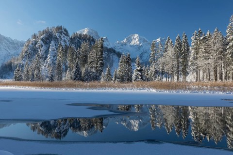Ameisstein (776 m) mountain at the Lake Almsee in winter. The lake is frozen and snow covered,