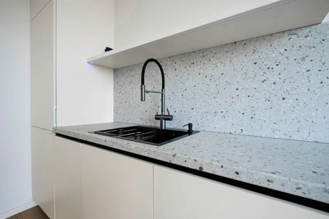 A sleek kitchen area showcases a minimalist design with a modern countertop and stylish black sink.