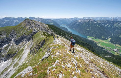 Mountaineer on the summit ridge of the Unnütz, behind Achensee and summit of the Seekarspitze